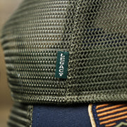 The Green Legacy Tag on the New Jersey Ocean City Sunset Mesh Back Trucker Hat | Navy Blue And Olive Mesh Trucker Hat