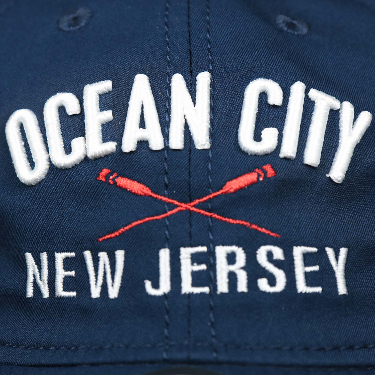 The Ocean City New Jersey Wordmark and Ocean City Crossed Oars Logo on the Ocean City New Jersey Wordmark Crossed Oars Logo Dad Hat | Navy Blue Dad Hat
