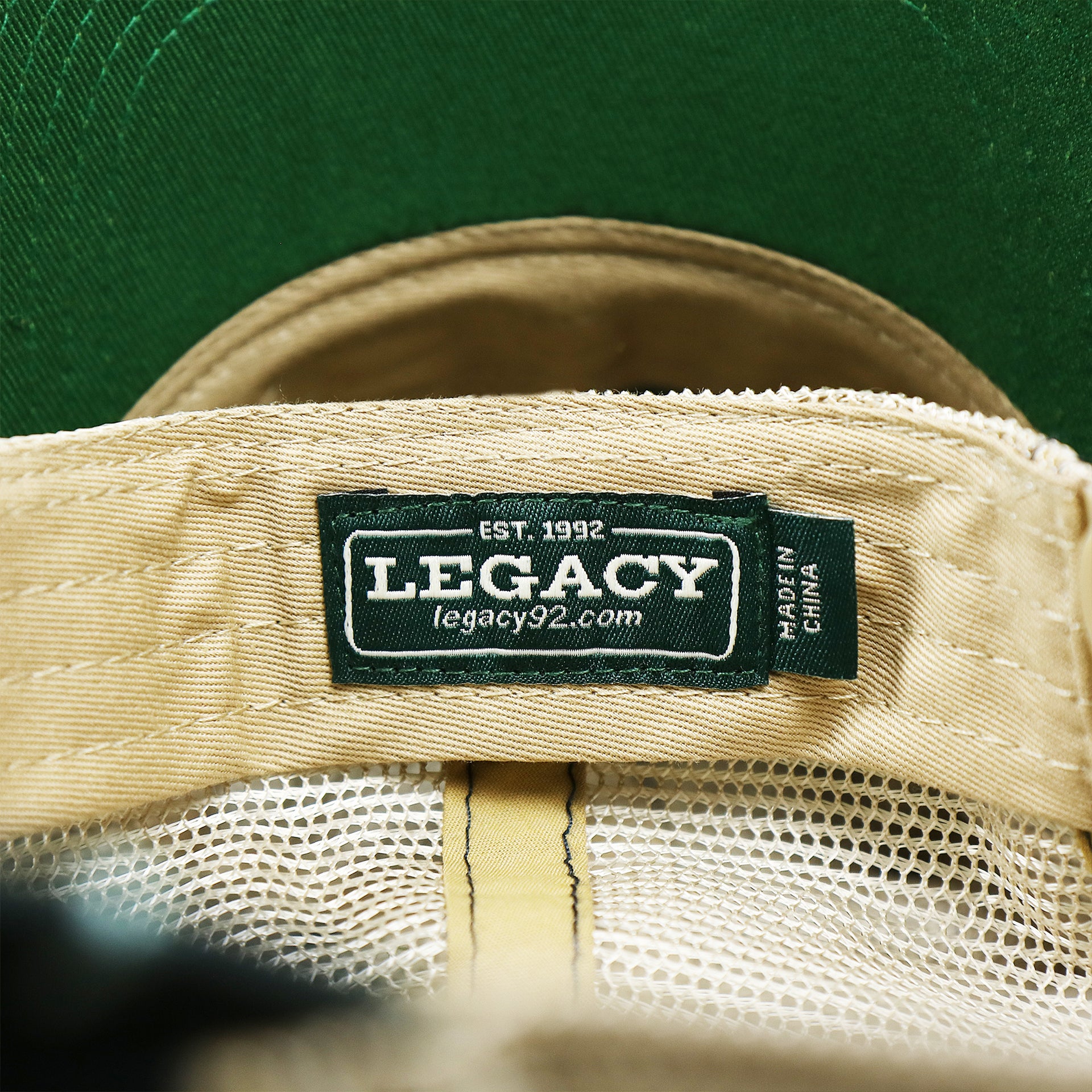 The Legacy Tag on the Ocean City Sunset Patch Fish Print Khaki Mesh Back Trucker Hat | Navy Blue Trucker Hat