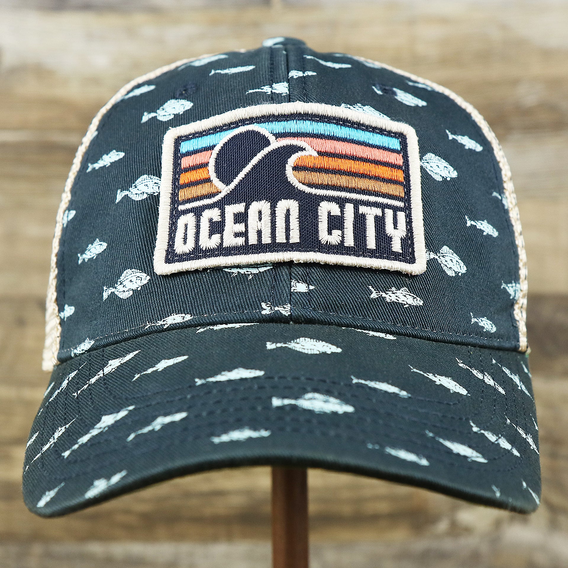 The front of the Ocean City Sunset Patch Fish Print Khaki Mesh Back Trucker Hat | Navy Blue Trucker Hat