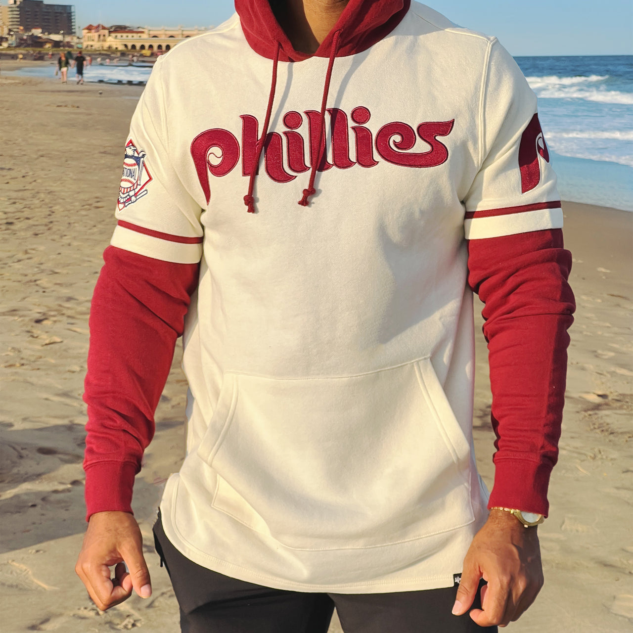 The front of the Cooperstown Philadelphia Phillies Wordmark Retro Phillies Colorway Trifecta Shortstop Layered Hoodie With MLB Side Patch | Cream And Maroon Pullover Hoodie