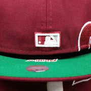 The MLB Batterman Logo on the Cooperstown Philadelphia Phillies Wordmark Side Split Vintage Green Bottom With Phillies Embroidered Undervisor Fitted Cap | Maroon Blue 59Fifty Cap
