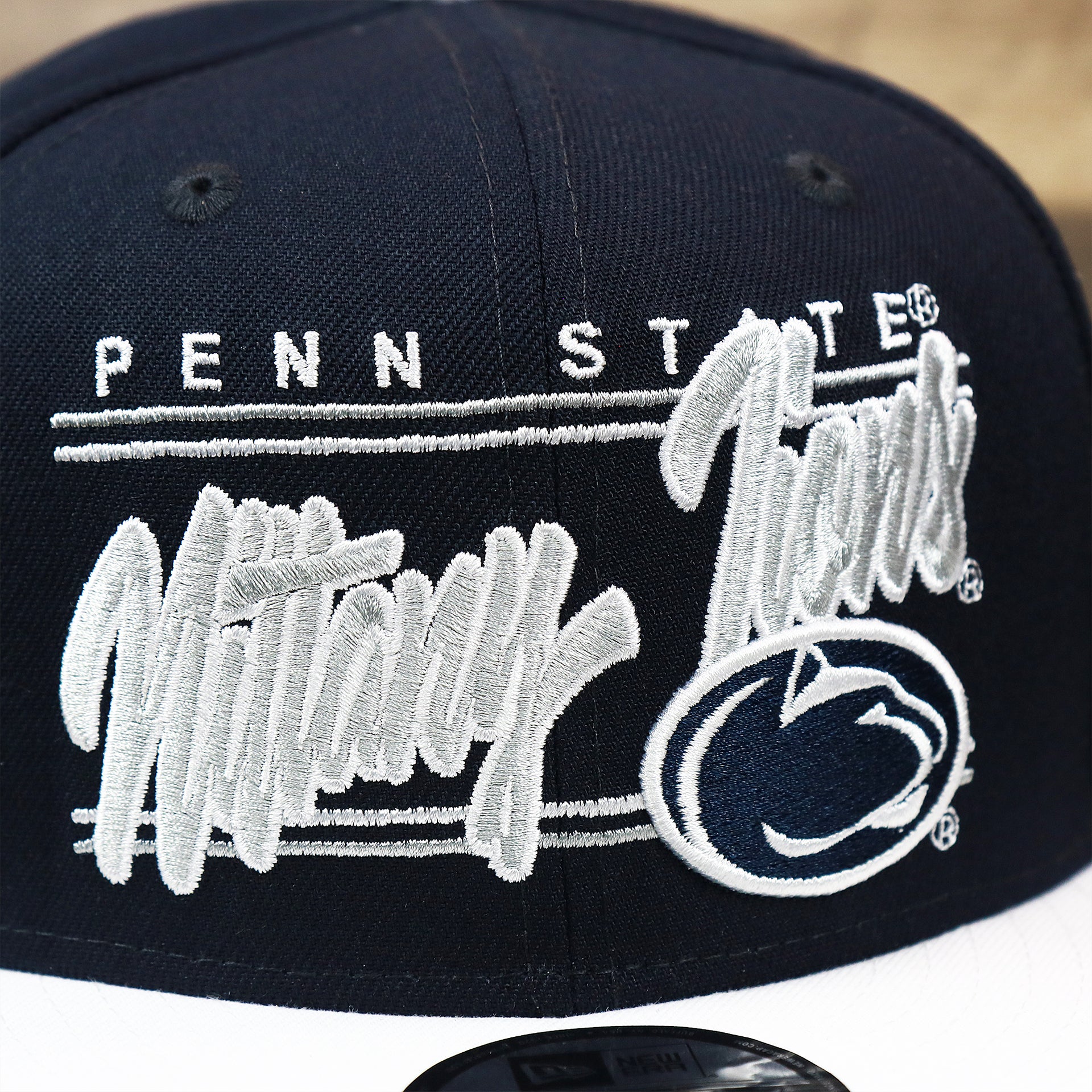 The Nittany Lions Team Script on the Penn State Nittany Lions Team Script Gray Bottom 9Fifty Snapback | Navy Blue And White Snap Cap