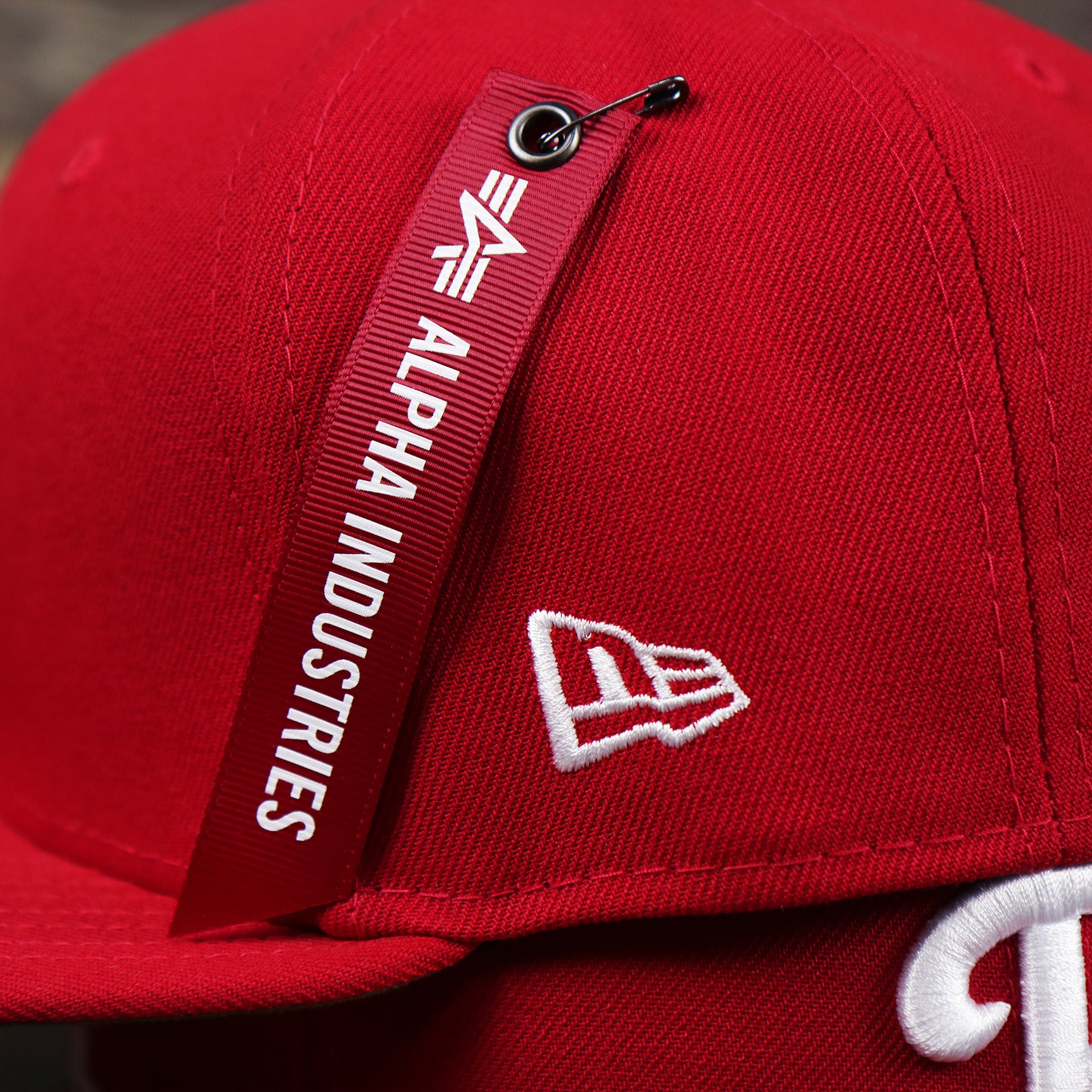 The New Era Logo and the Alpha hangtag on the Philadelphia Phillies Alpha Industries Side Patch Army Green Undervisor 59FIfty Fitted Cap With Hangtag | Red 59FIfty Cap