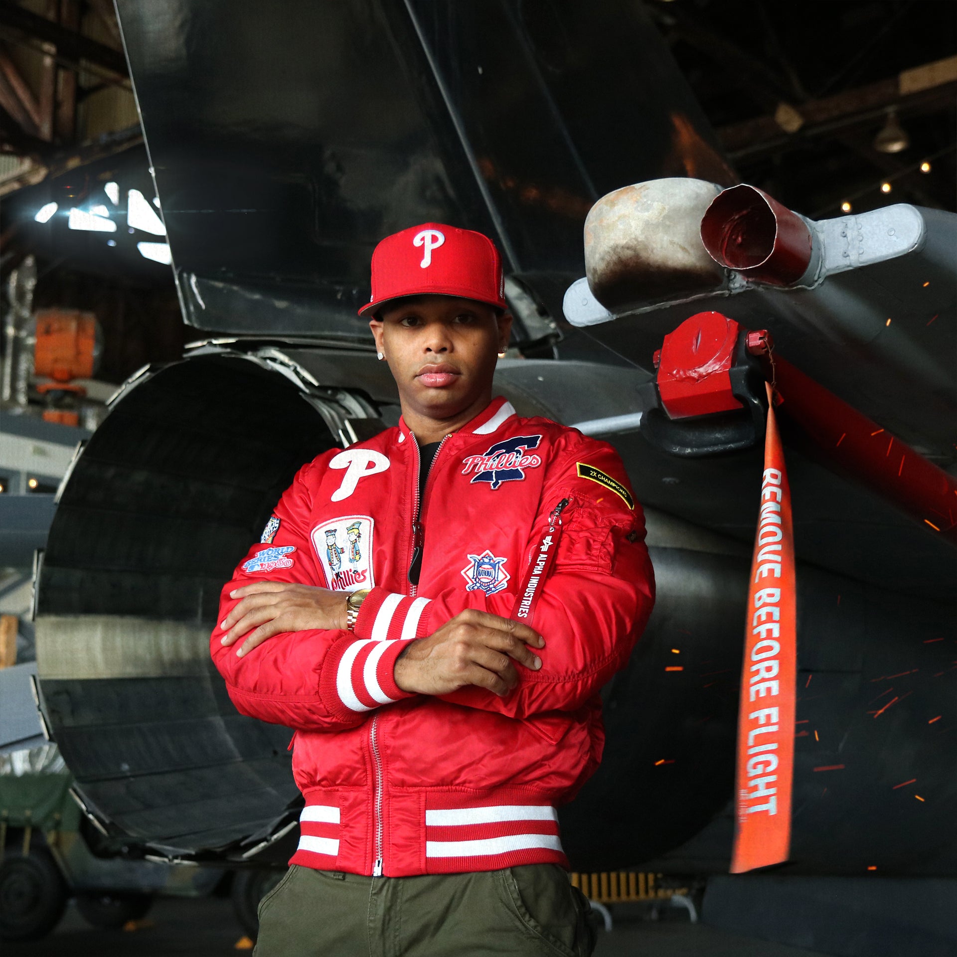 The Philadelphia Phillies MLB Patch Alpha Industries Reversible Bomber Jacket With Camo Liner | Red Bomber Jacket behind a jet