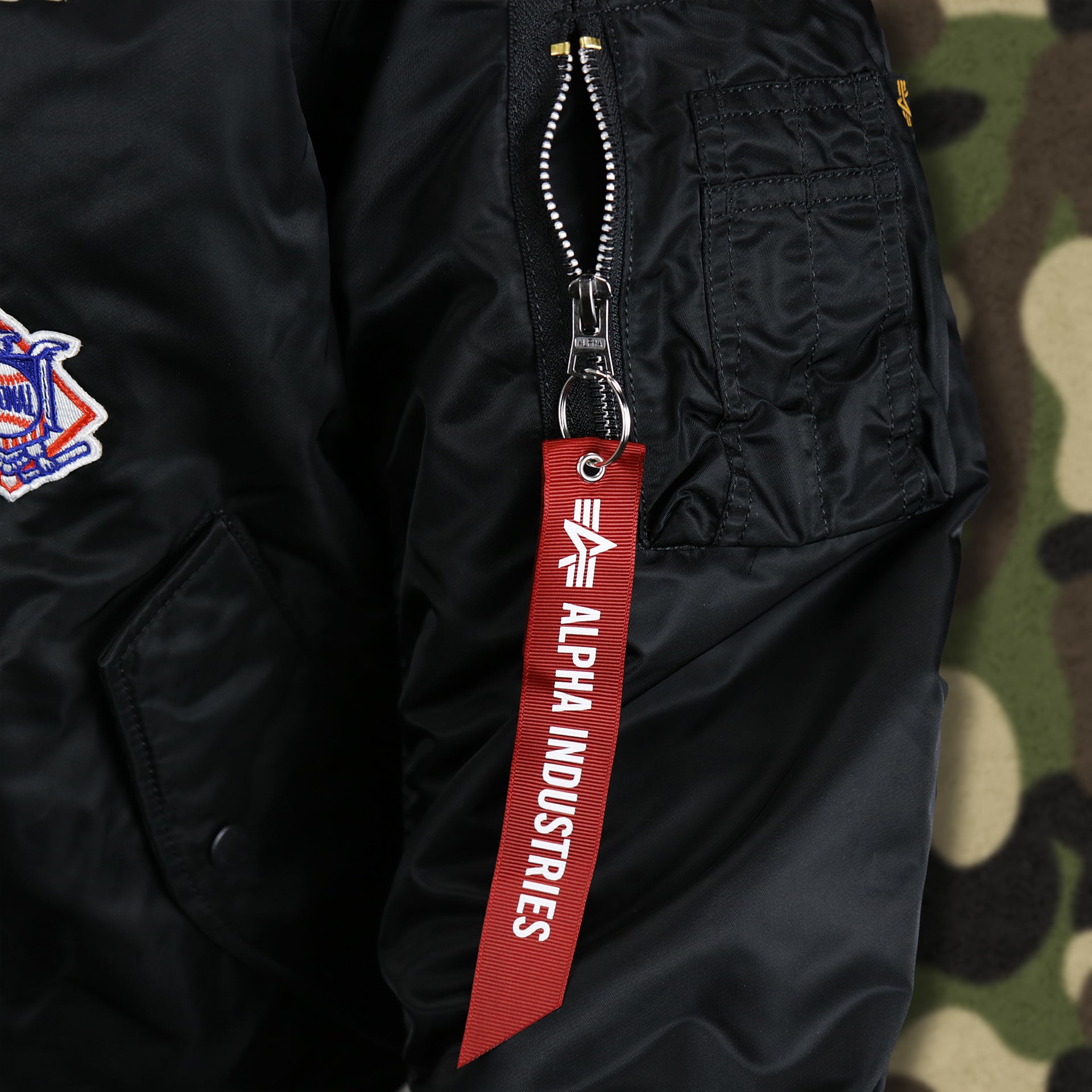 The Alpha Industries Hangtag on the Cooperstown Philadelphia Phillies MLB Patch Alpha Industries Reversible Bomber Jacket With Camo Liner | Black Bomber Jacket