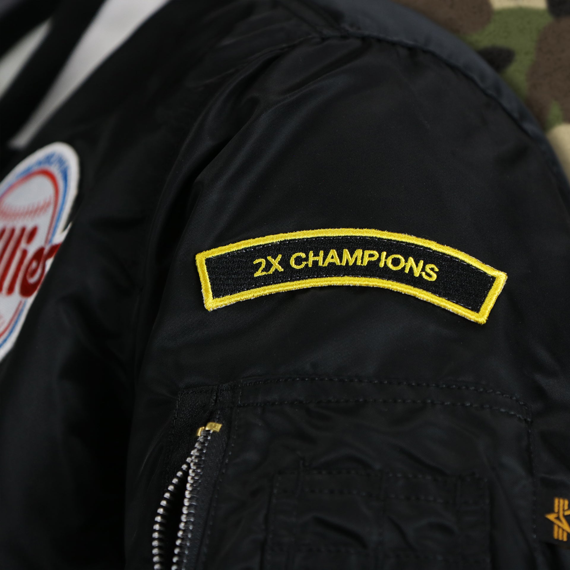 The 2x Champions Side Patch on the Cooperstown Philadelphia Phillies MLB Patch Alpha Industries Reversible Bomber Jacket With Camo Liner | Black Bomber Jacket
