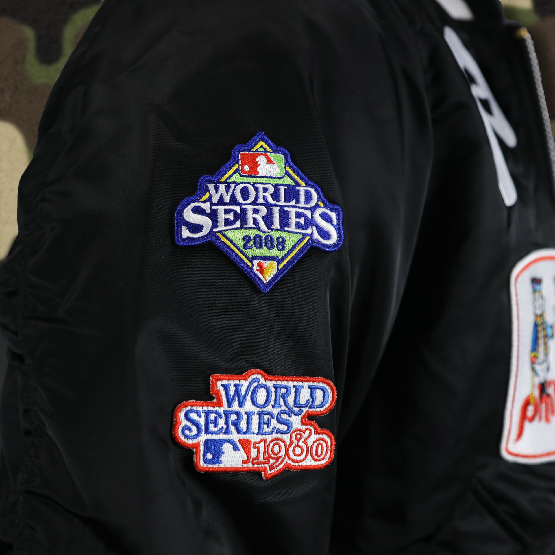 The World Series Side Patches on the Cooperstown Philadelphia Phillies MLB Patch Alpha Industries Reversible Bomber Jacket With Camo Liner | Black Bomber Jacket