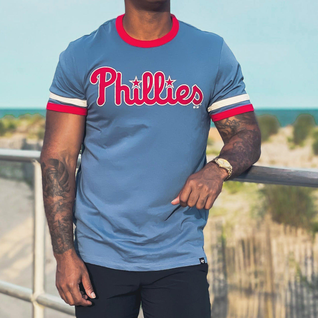 The front of the Philadelphia Phillies Wordmark Logo Otis Ringer Striped TShirt | Cadet Blue TShirt