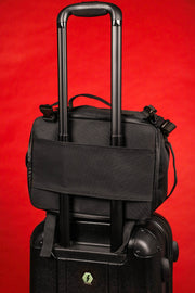 The backside of the Black Box Media Camera Travel Bag / Cap Carrier with Custom Dividers and Glasses Case on a suit case