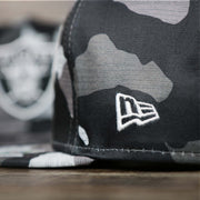 A close up of the New Era Logo on the Los Angeles Raiders NFL OnField Summer Training 2022 Camo 9Fifty Snapback | Black Camo 9Fifty
