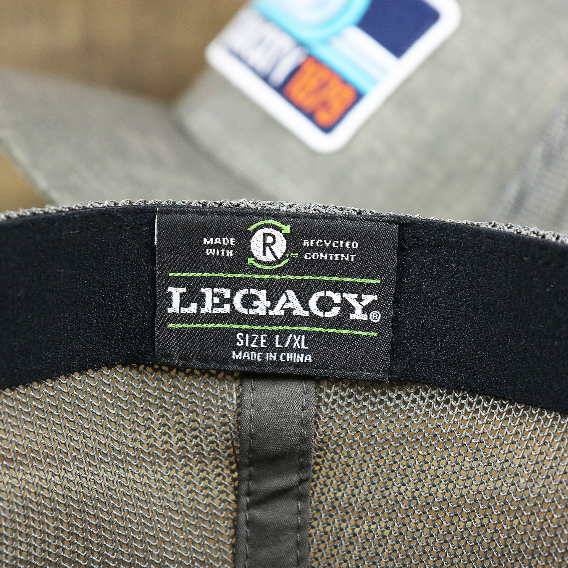 The Legacy Tag on the OCNJ Ocean City 1879 Sunset Wave Logo Mesh Stretch FIt Hat | Dark Green And Dark Grey Stretch Fit Hat