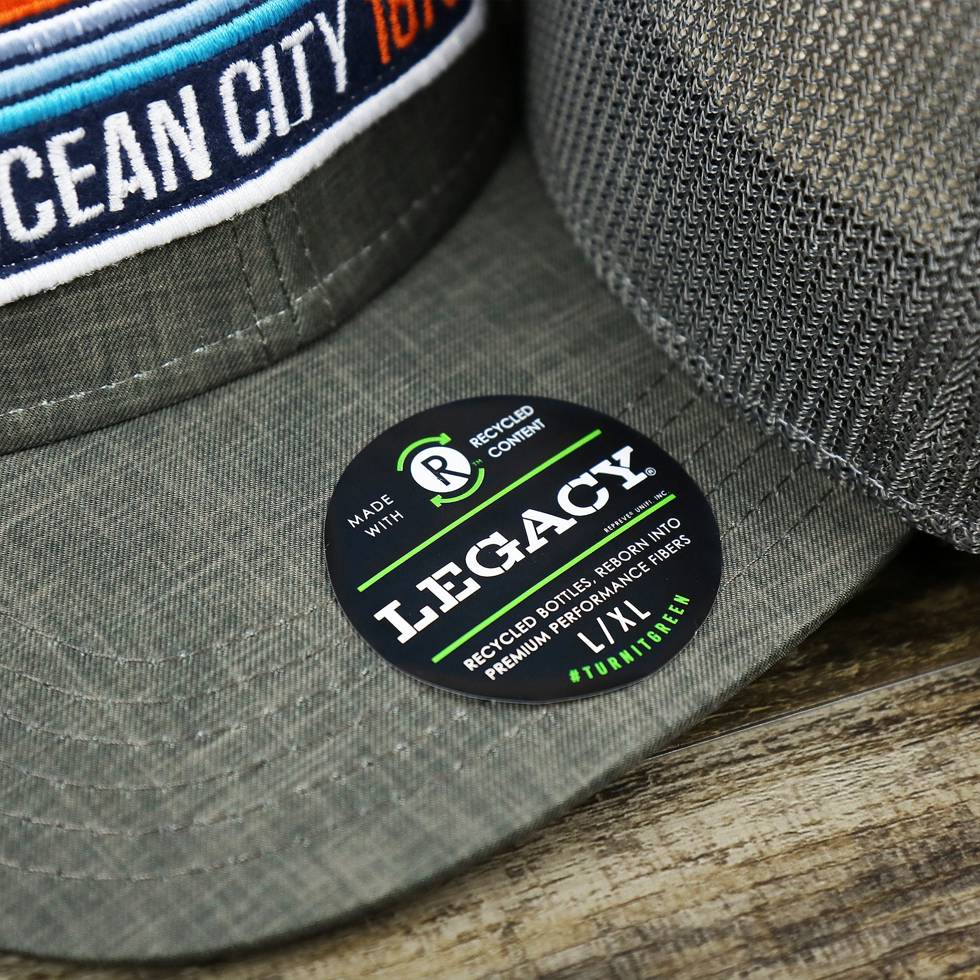The Legacy Sticker on the OCNJ Ocean City 1879 Sunset Wave Logo Mesh Stretch FIt Hat | Dark Green And Dark Grey Stretch Fit Hat
