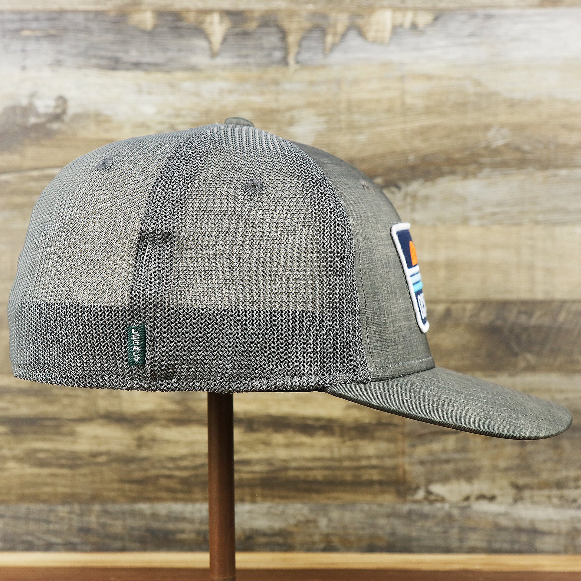 The wearer's right on the OCNJ Ocean City 1879 Sunset Wave Logo Mesh Stretch FIt Hat | Dark Green And Dark Grey Stretch Fit Hat