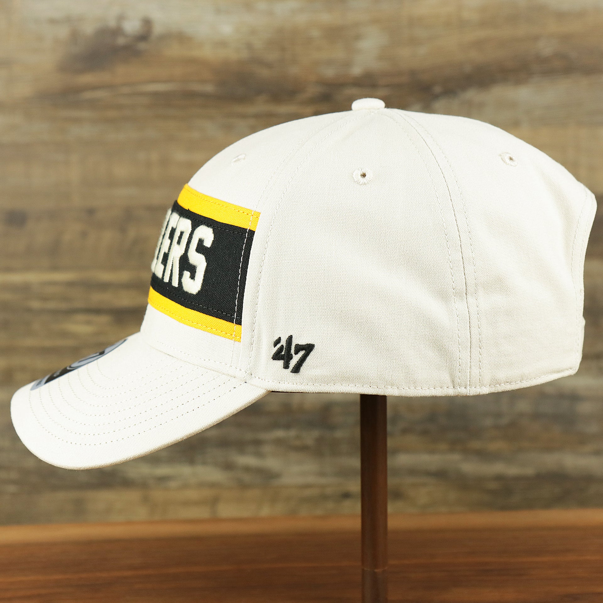 The wearer's left on the Throwback Pittsburgh Steelers Striped Wordmark Legacy Steelers Side Patch Crossroad Dad Hat | Bone Dad Hat
