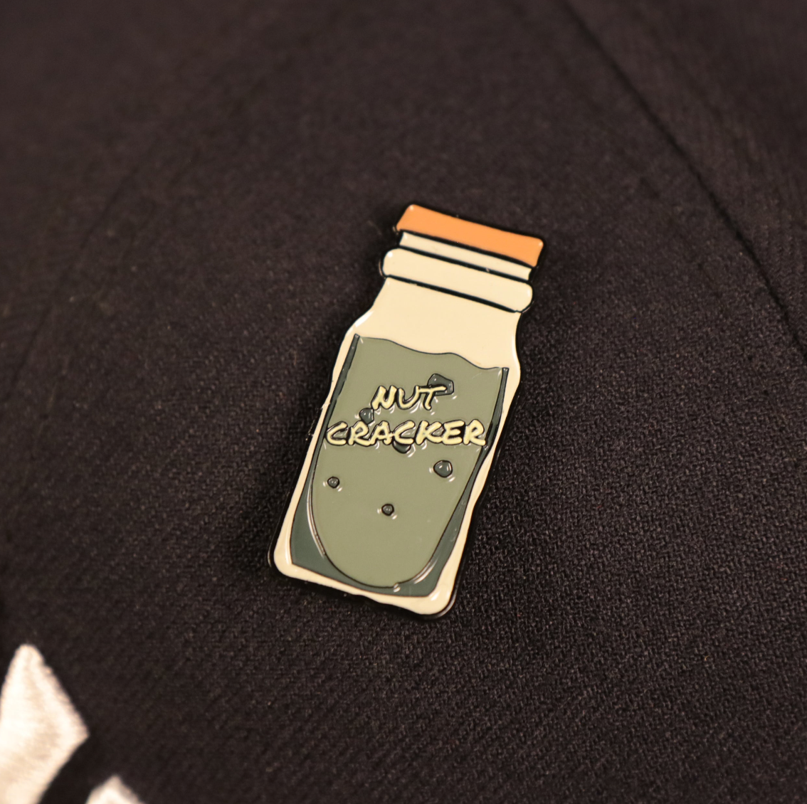 A close up of the New York Nut Cracker Drink Fitted Cap Pin | Enamel Pin For Hat 