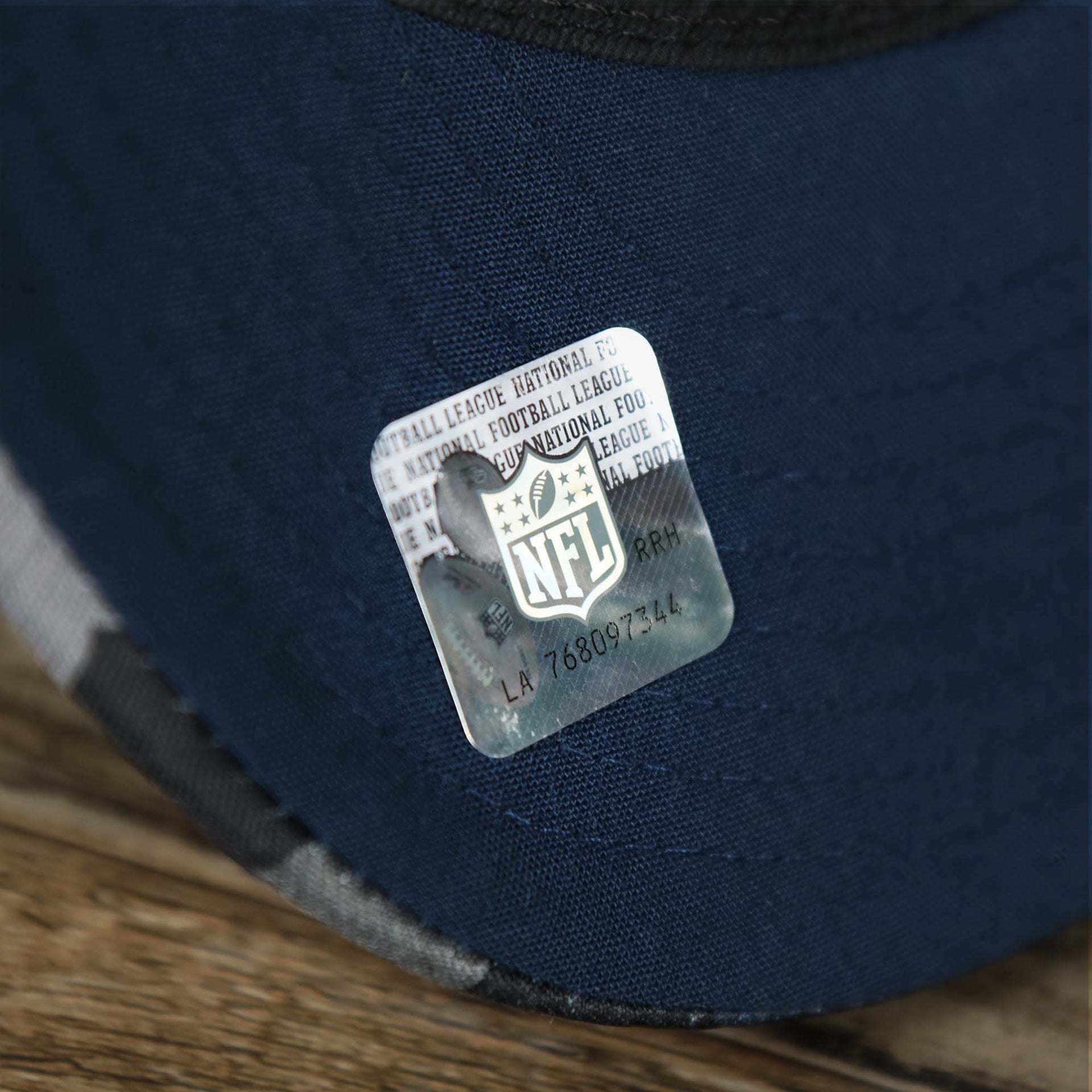 The NFL Sticker on the visor of the Seattle Seahawks NFL OnField Summer Training 2022 Camo 9Fifty Snapback | Navy Blue Camo 9Fifty