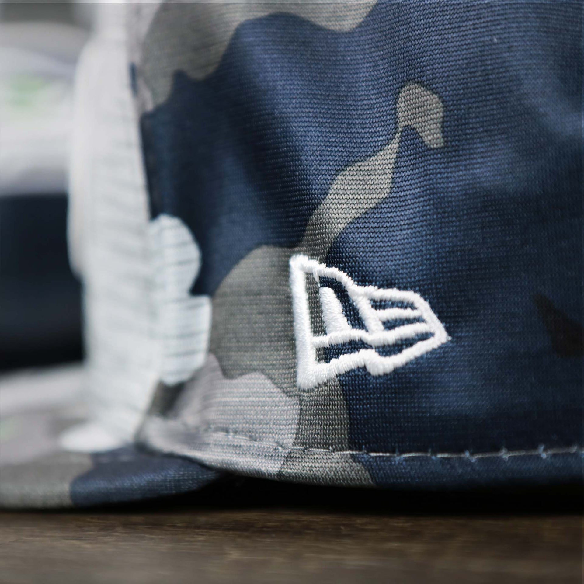 A close up of the New Era Logo on the Seattle Seahawks NFL OnField Summer Training 2022 Camo 9Fifty Snapback | Navy Blue Camo 9Fifty