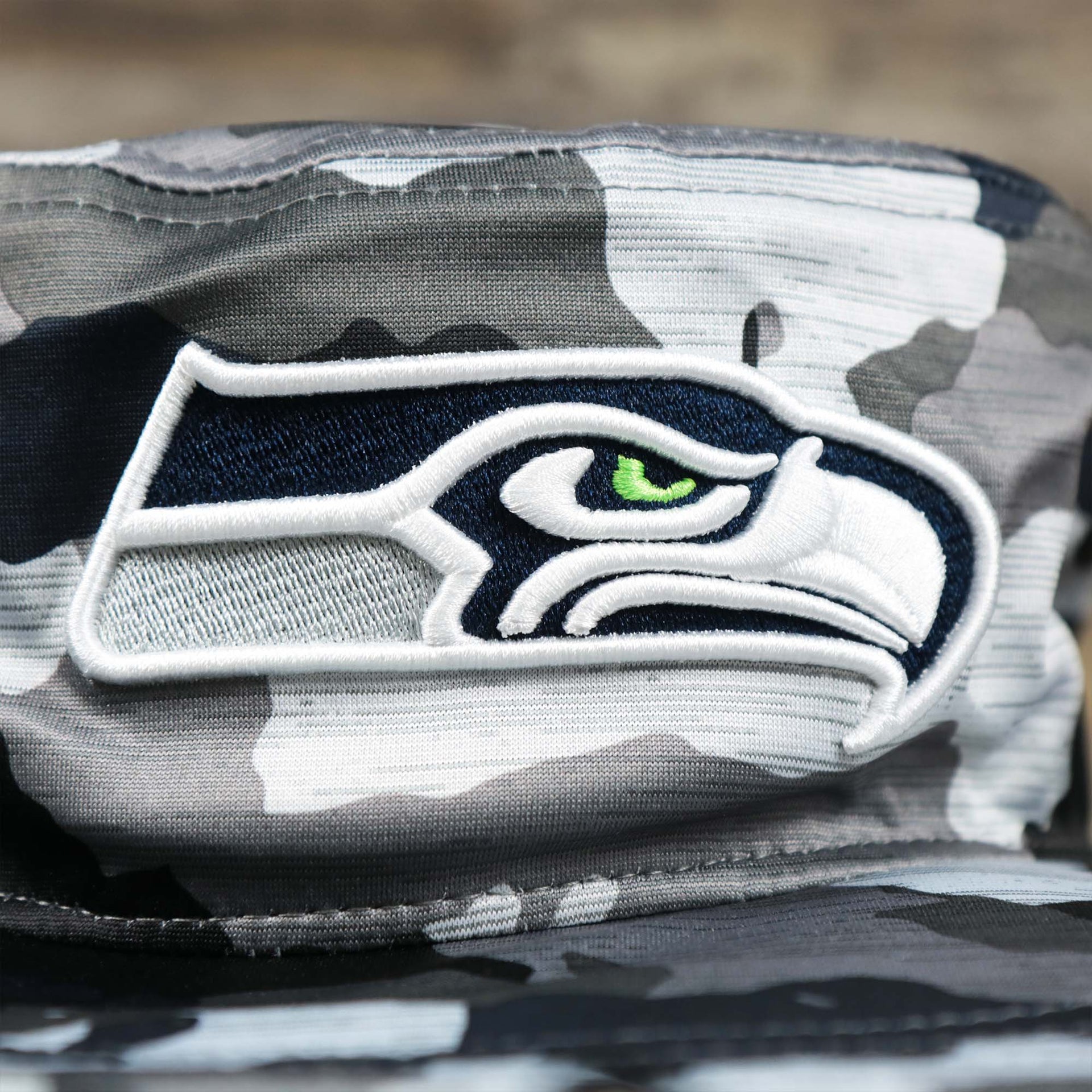 The Seahawks logo on the Seattle Seahawks NFL Summer Training Camp 2022 Camo Bucket Hat | Navy Bucket Hat