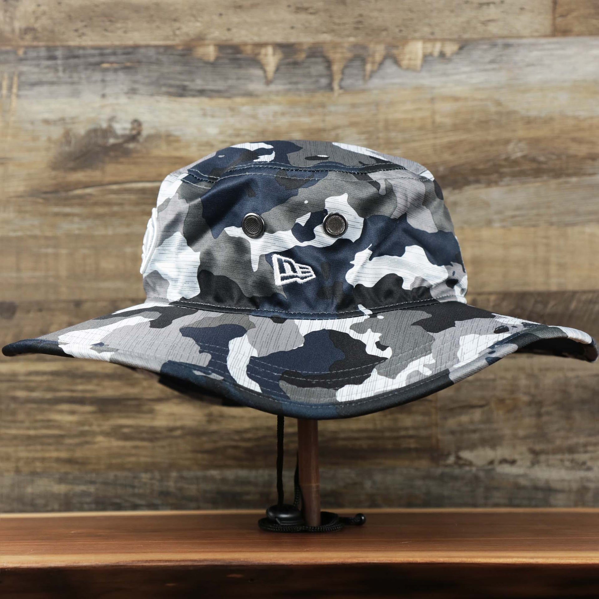 The wearer's left on the Seattle Seahawks NFL Summer Training Camp 2022 Camo Bucket Hat | Navy Bucket Hat