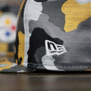 A close up of the New Era Logo on the Pittsburgh Steelers NFL OnField Summer Training 2022 Camo 9Fifty Snapback | Yellow Camo 9Fifty