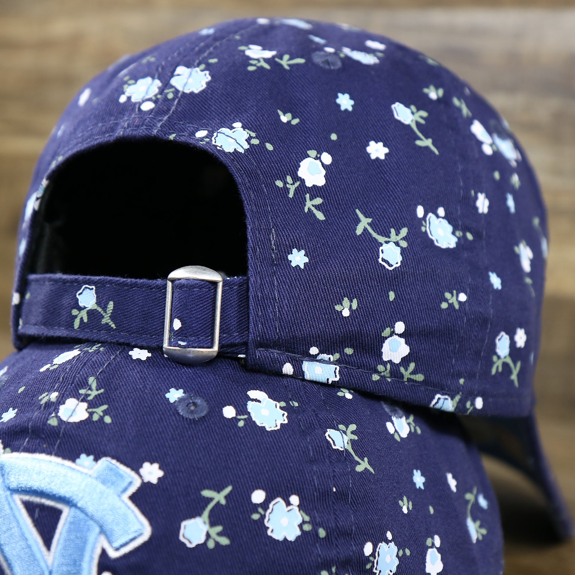 The Adjustable Strap with Metallic Buckle on the Women’s North Carolina Tar Heels All Over Micro Floral Print 9Twenty Dad hat | Navy Blue 9Twenty Hat