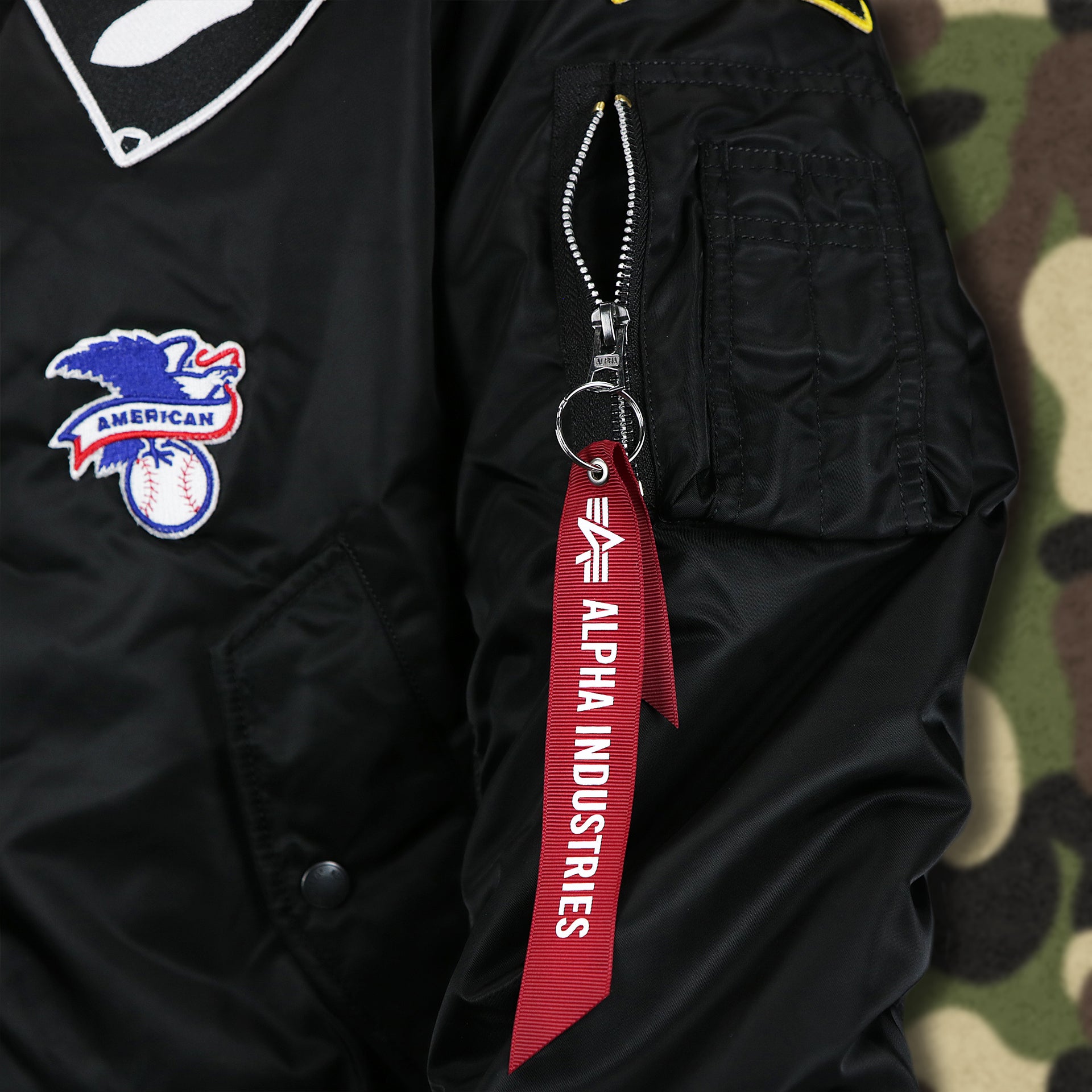 The Alpha Industries Flight Tag on the Chicago White Sox MLB Patch Alpha Industries Reversible Bomber Jacket With Camo Liner | Black Bomber Jacket