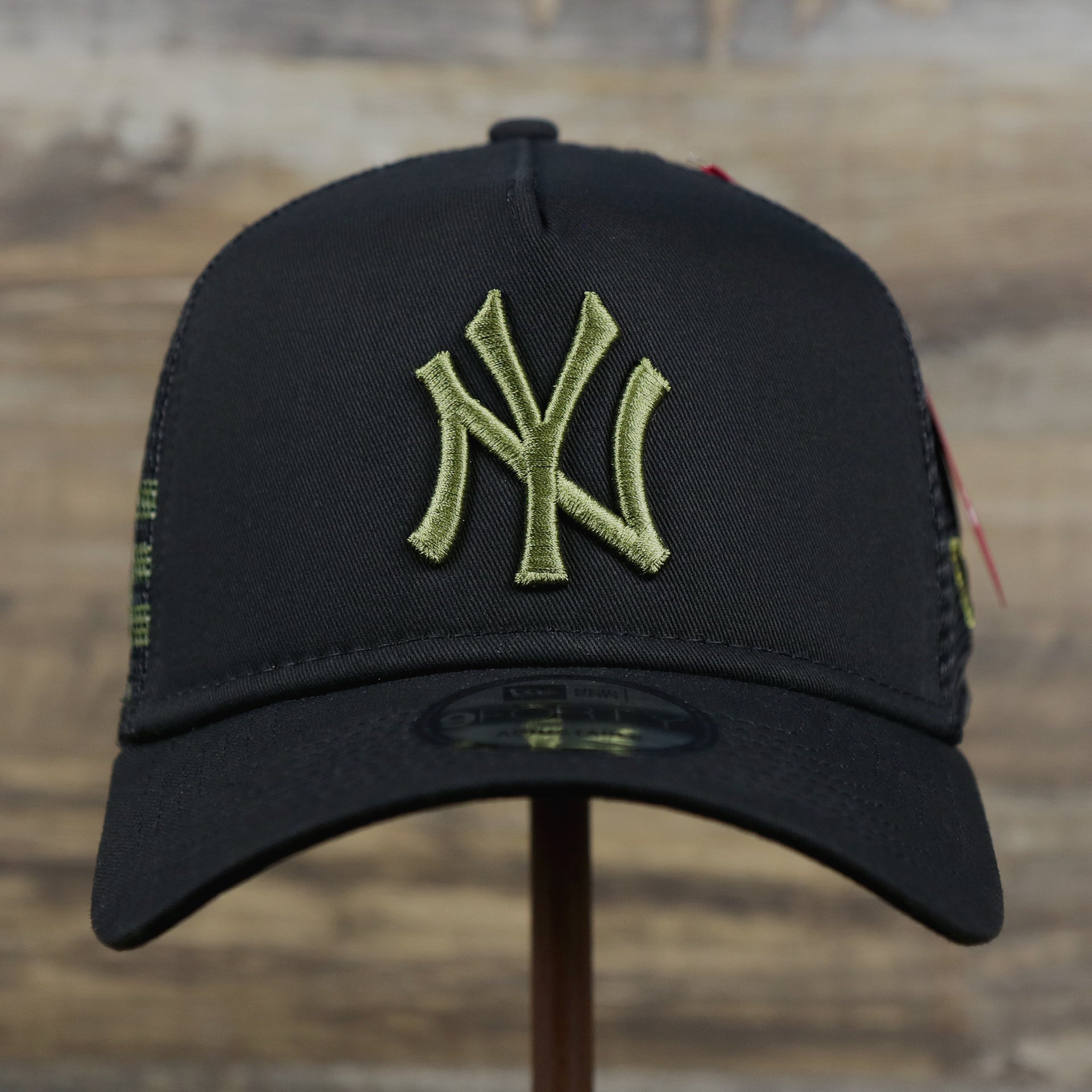 The front of the New York Yankees Alpha Industries Flying A Mesh Print 9Forty Trucker Hat With Flight Tag | Black Trucker Hat
