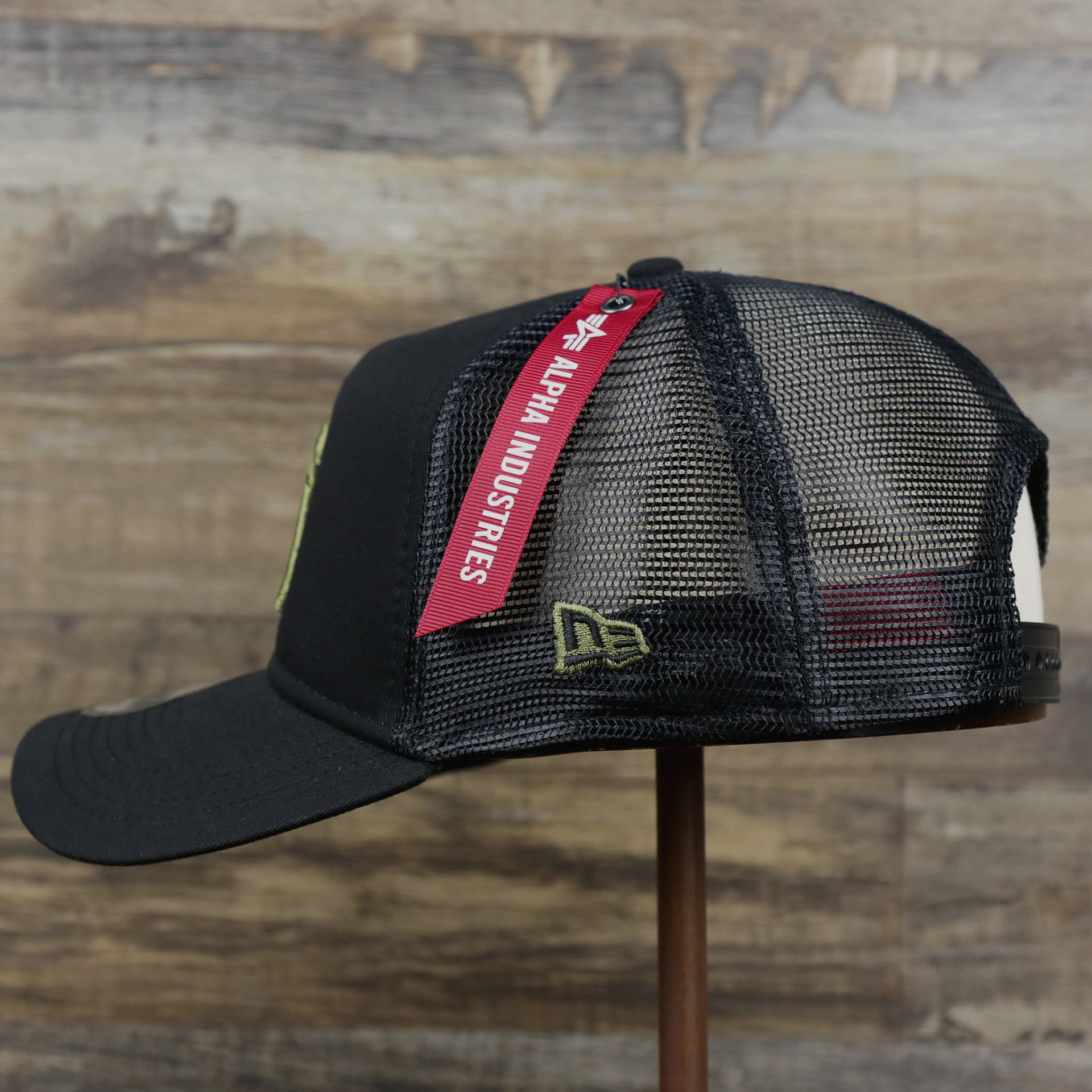 The Wearer's left on the New York Yankees Alpha Industries Flying A Mesh Print 9Forty Trucker Hat With Flight Tag | Black Trucker Hat