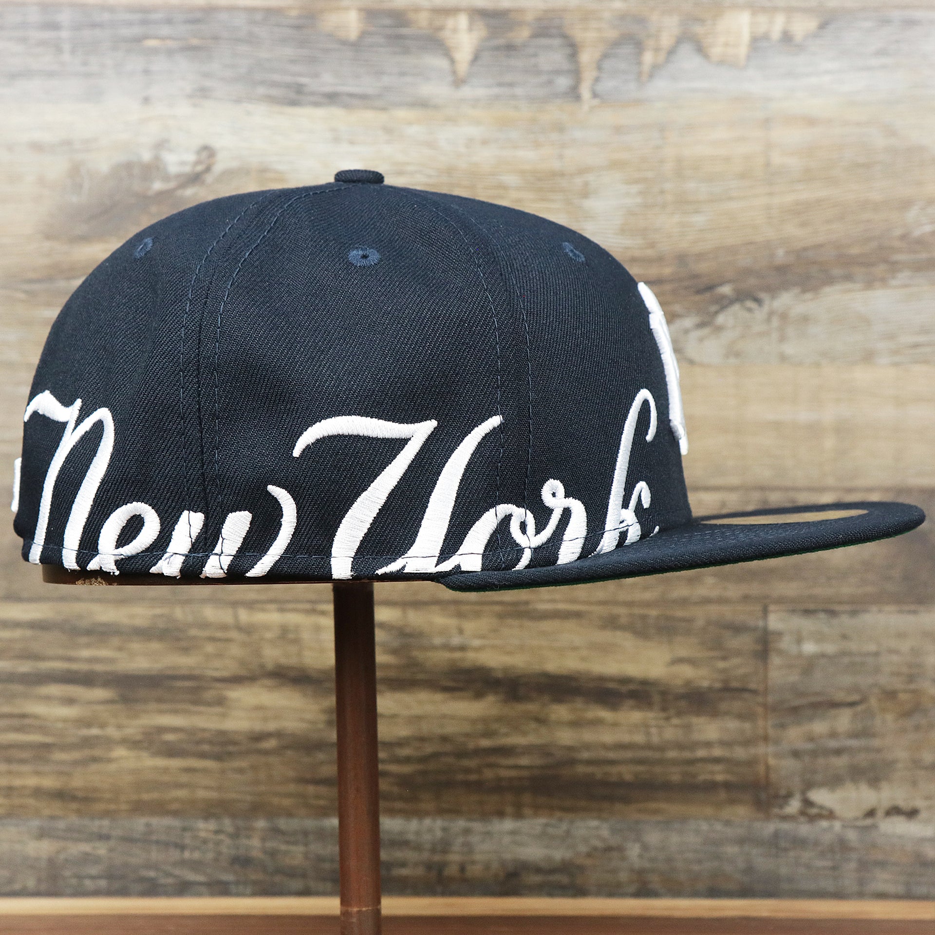 The wearer's right on the New York Wordmark Side Split New York Yankees Vintage Green Bottom Embroidered Undervisor Fitted Cap | Navy Blue 59Fifty Cap