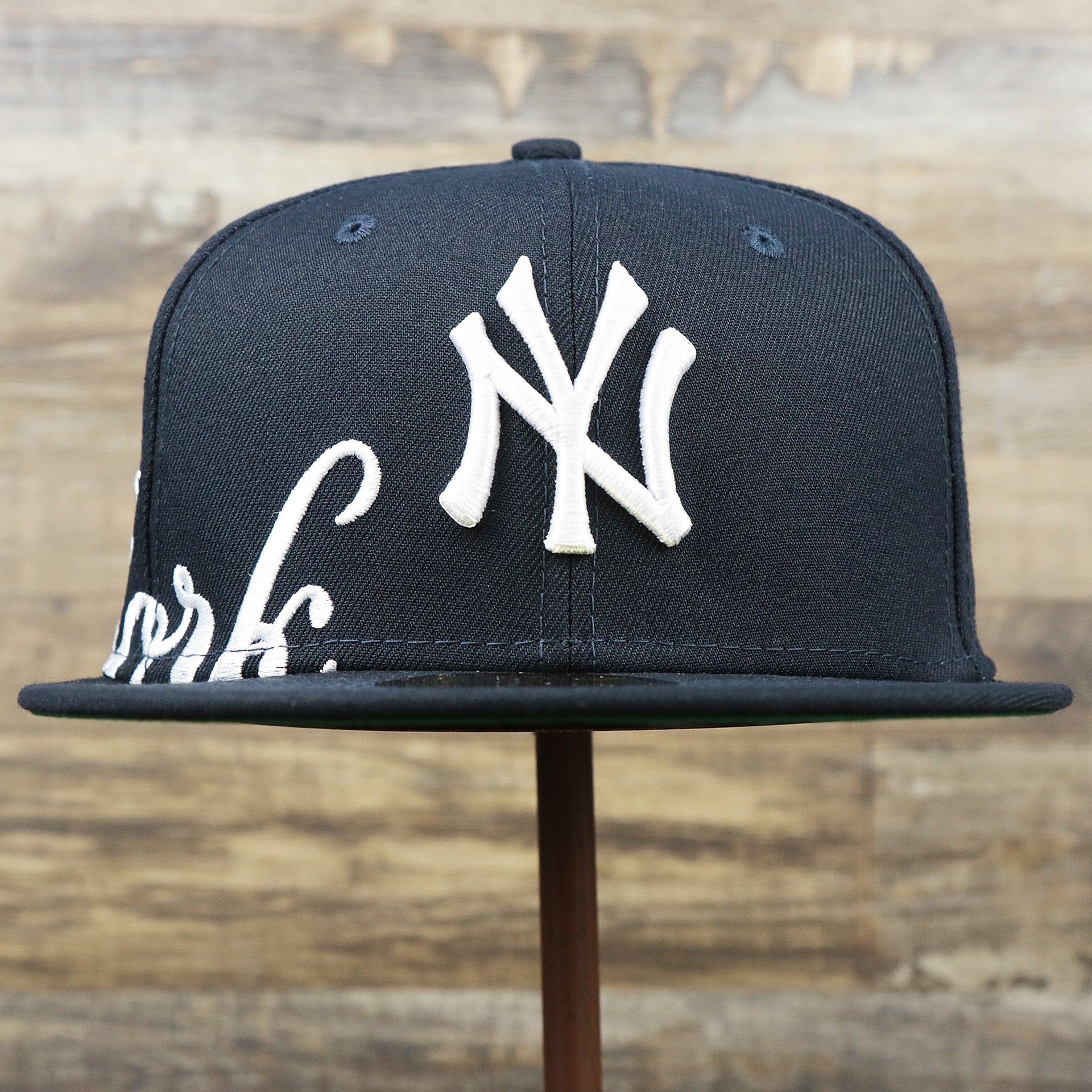 The front of the New York Wordmark Side Split New York Yankees Vintage Green Bottom Embroidered Undervisor Fitted Cap | Navy Blue 59Fifty Cap