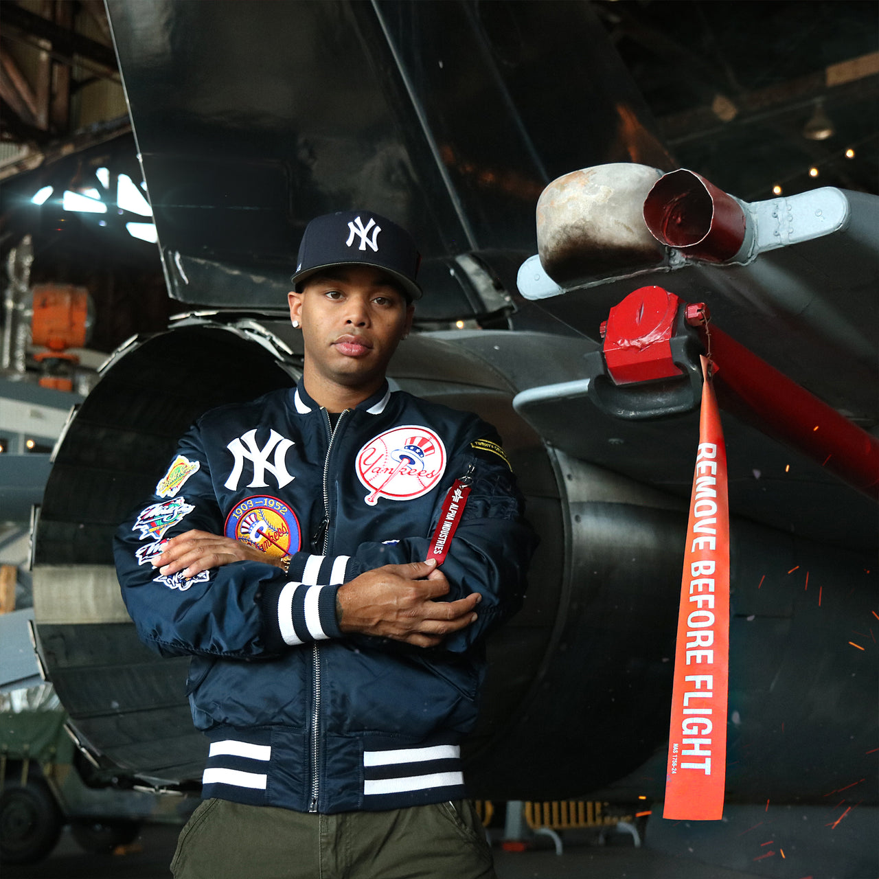 The New York Yankees MLB Patch Alpha Industries Reversible Bomber Jacket With Camo Liner | Navy Blue Bomber Jacket behind a jet