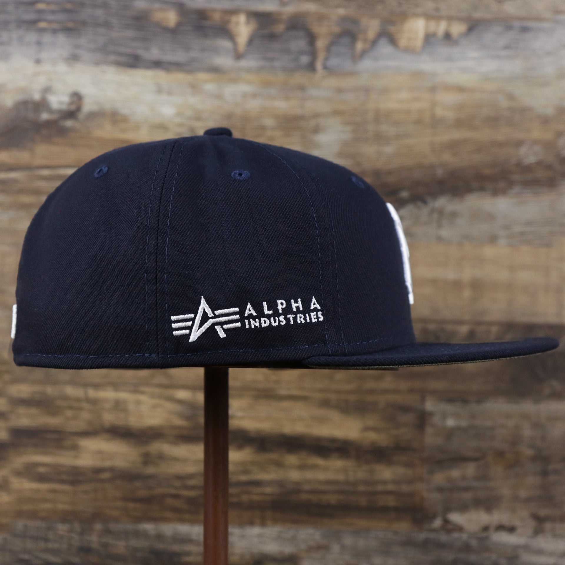 The wearer's left on the New York Yankees Alpha Industries Side Patch Army Green Undervisor 59FIfty Fitted Cap With Hangtag | Navy Blue 59FIfty Cap