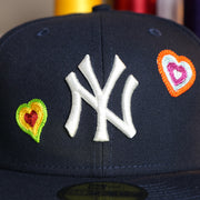Close up of the Yankees logo on the New York Yankees All Over Embroidered Chain Stitch Heart Pink Bottom 59Fifty Fitted Cap | Navy 59Fifty Cap