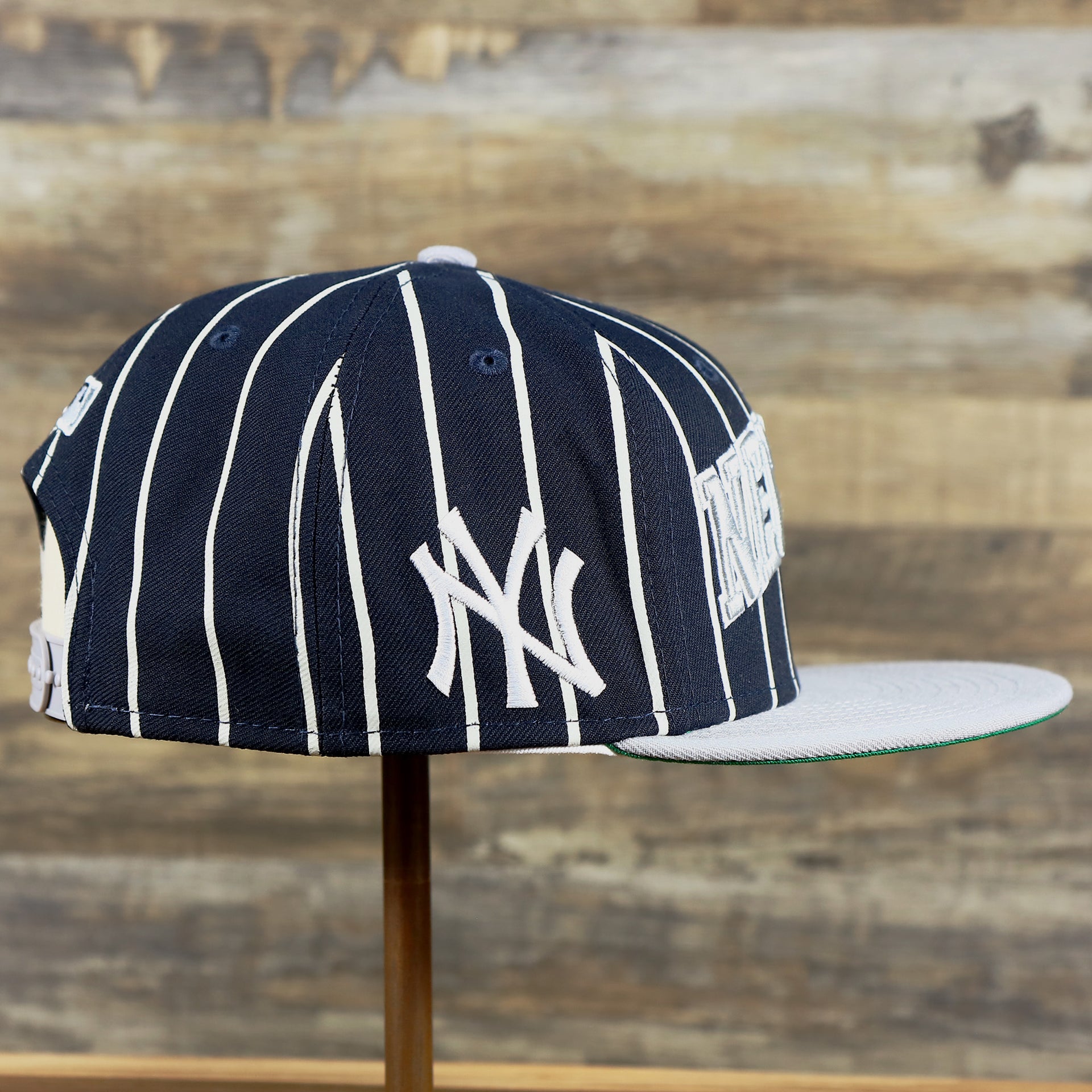 The wearer's right of the New York Yankees City Arch Striped 9Fifty Snapback Cap | Pin Stripe 9Fifty Cap