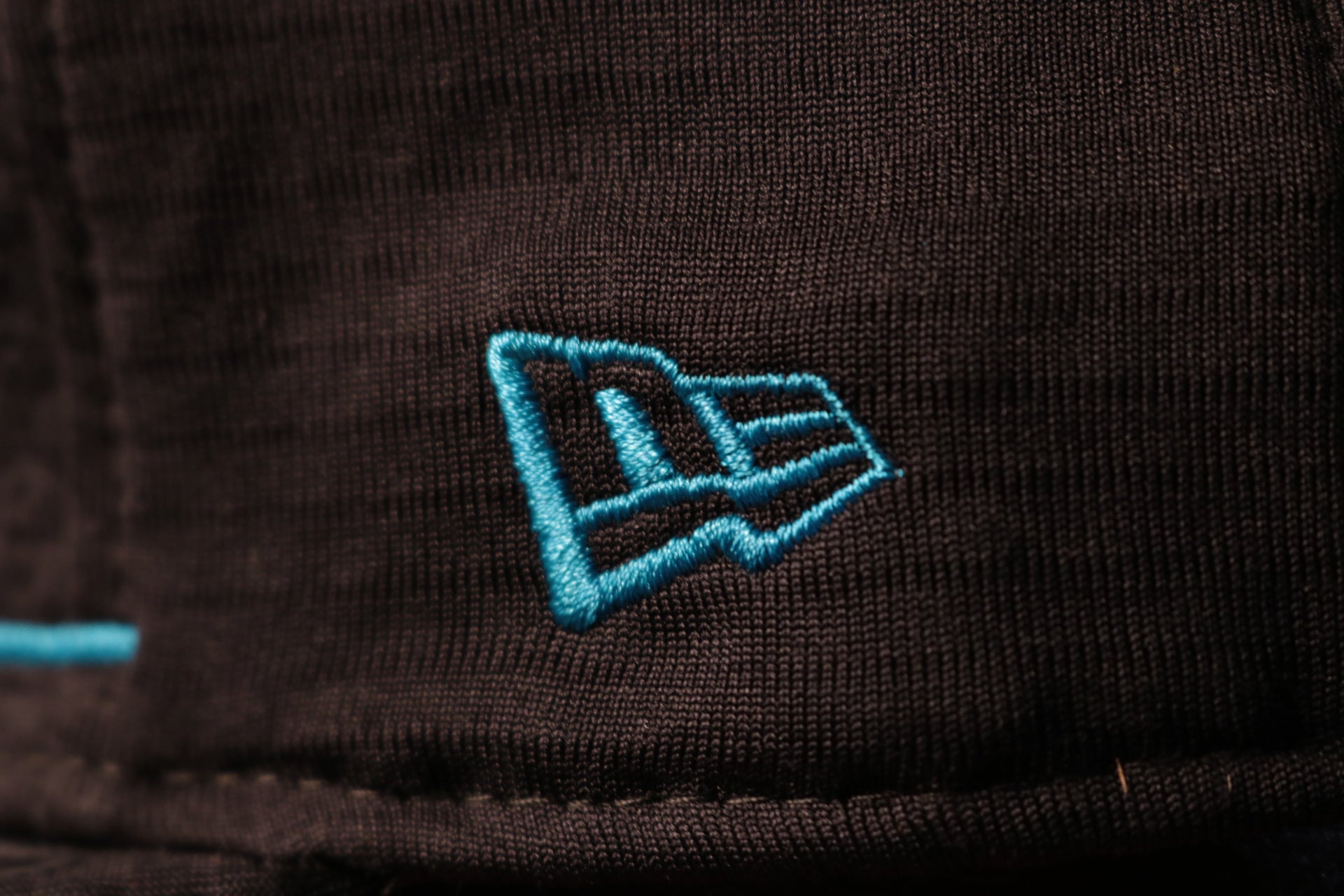The new era logo is embroidered in teal Panthers 2020 Training Camp Snapback Hat | Carolina Panthers 2020 On-Field Black Training Camp Snap Cap