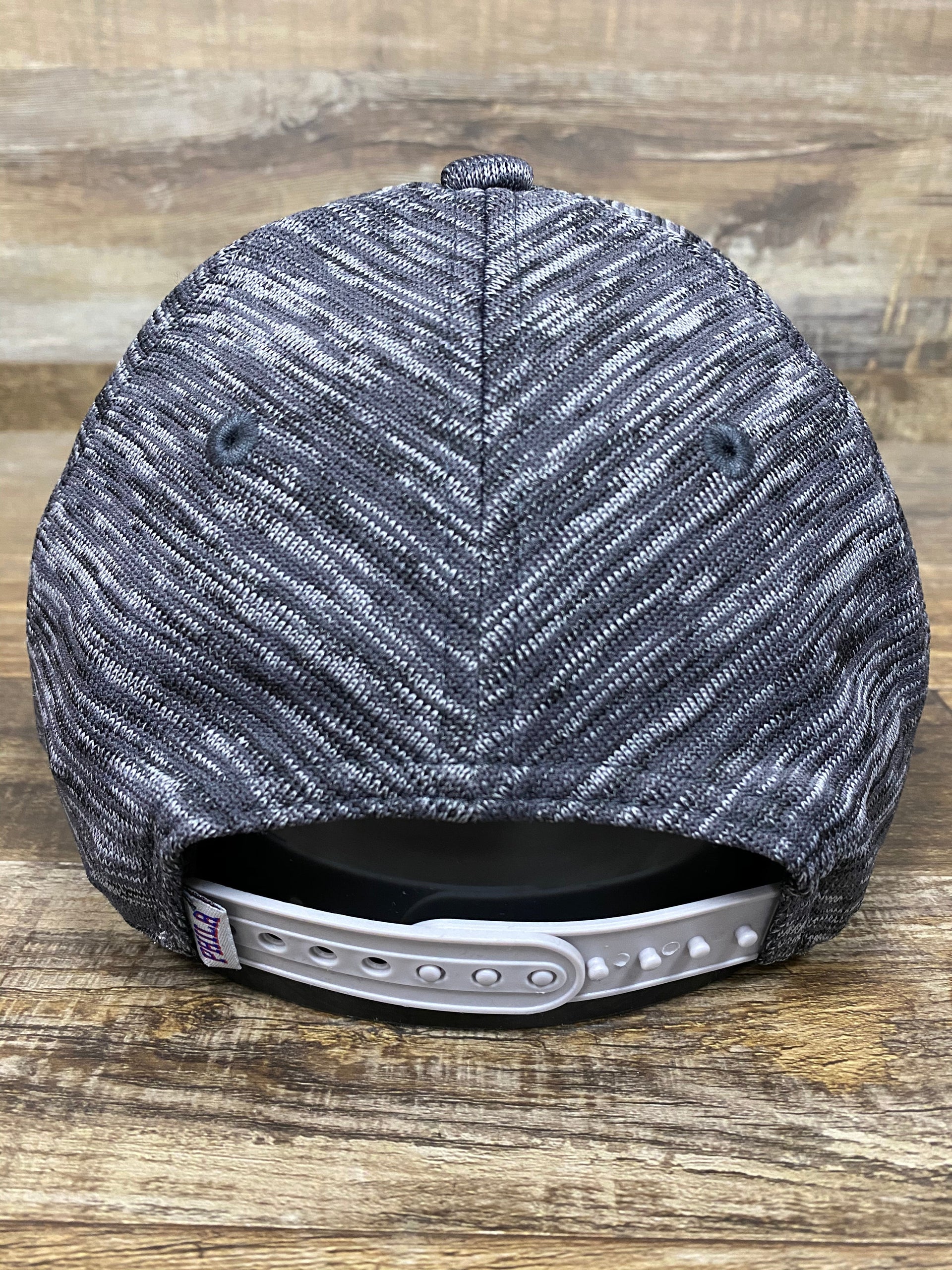 on the back of the Philadelphia Phillies Retro Logo Space-Dye Gray Trucker Dad Hat is space-dye cross-dyed gray stripes and an adjustable snap back