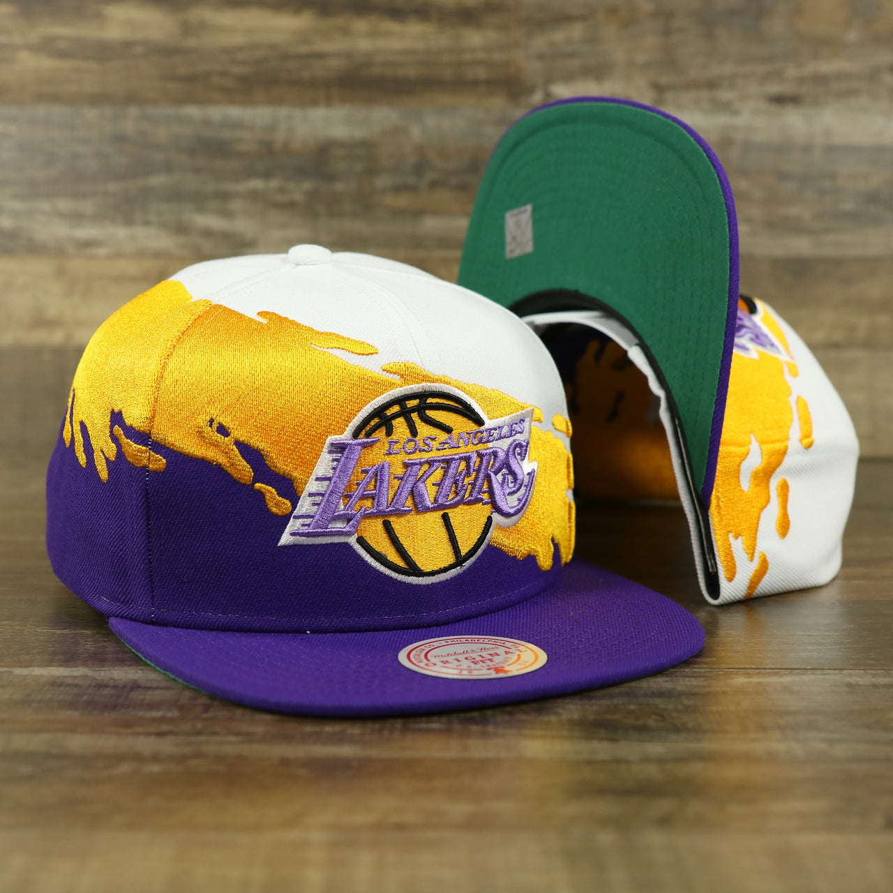 front and bottom of the Los Angeles Lakers Vintage Retro NBA Paintbrush Mitchell and Ness Snapback Hat | Purple/White/Yellow