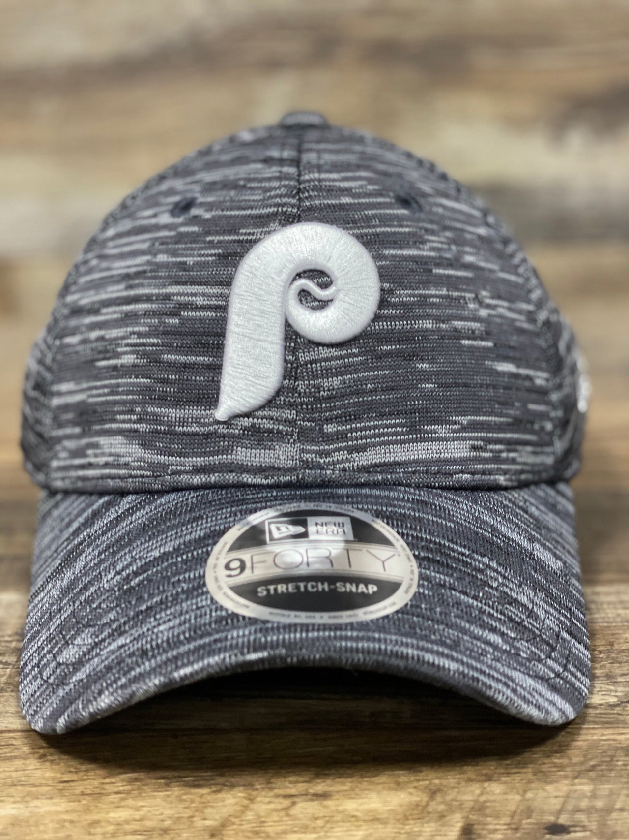 on the front of the Philadelphia Phillies Retro Logo Space-Dye Gray Trucker Dad Hat is a 1970s vintage Phils P logo