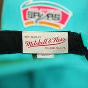 Mitchell and Ness label on the interior of the San Antonio Spurs Vintage Retro NBA Team Ground 2.0 Mitchell and Ness Snapback Hat | Teal