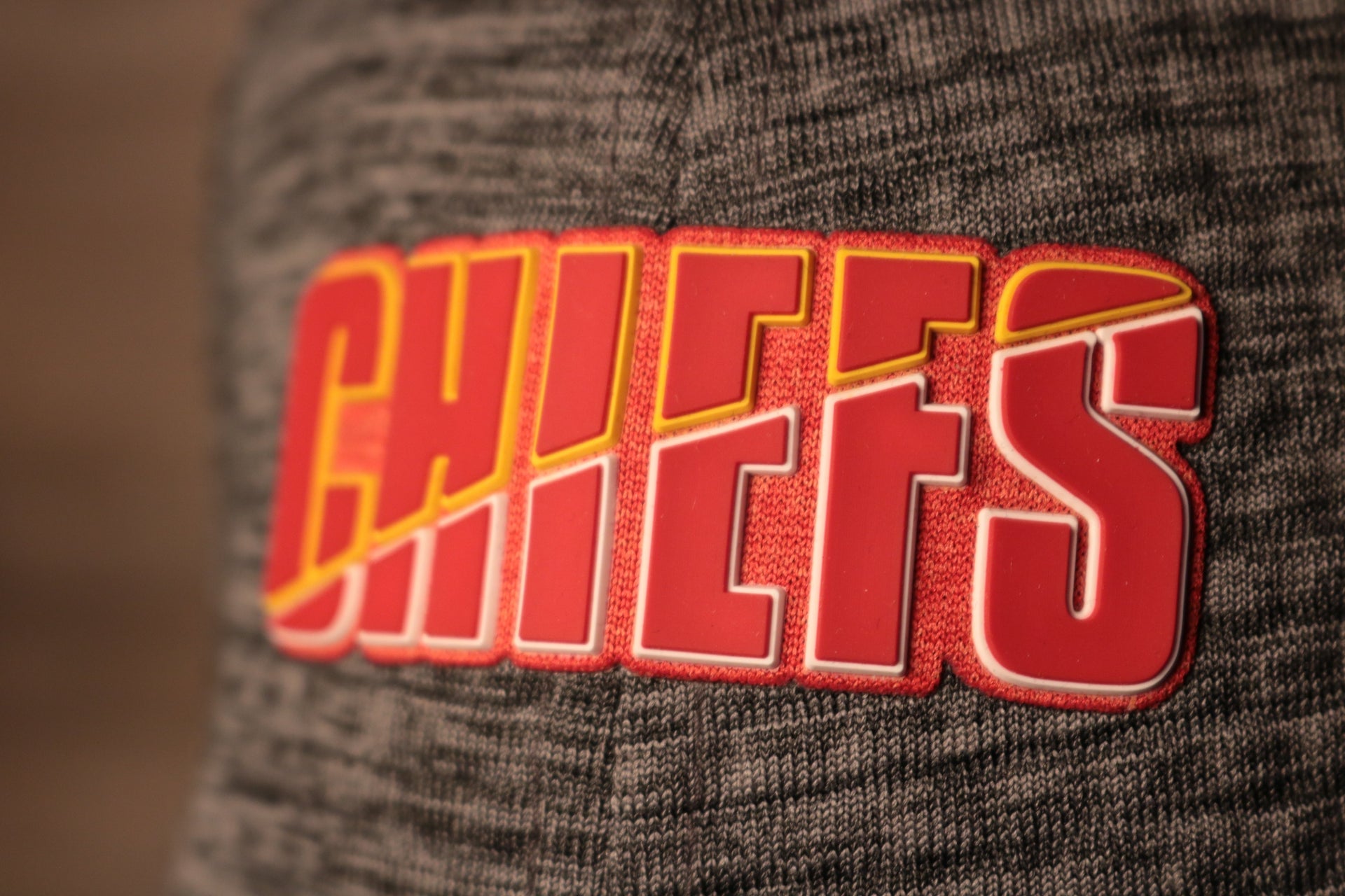 The chiefs name is red with a yellow and white outline Chiefs 2020 Training Camp Flexfit | Kansas City Chiefs 2020 On-Field Grey Training Camp Stretch Fit