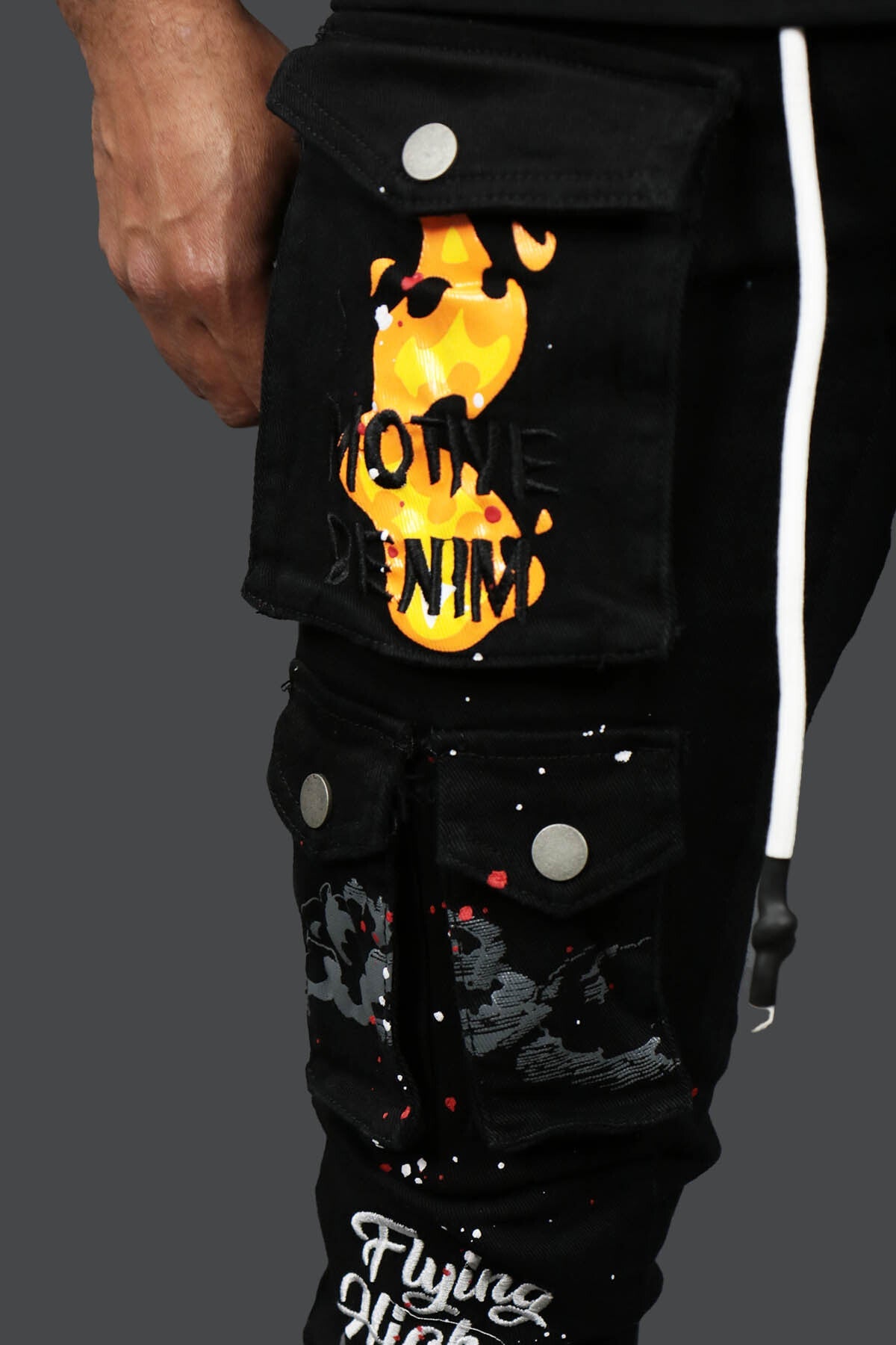 A close up of the wearer's right leg on the Fly High Custom Painted Cargo Denim Pants Motive Denim | Black | with 3 button clasp pocket