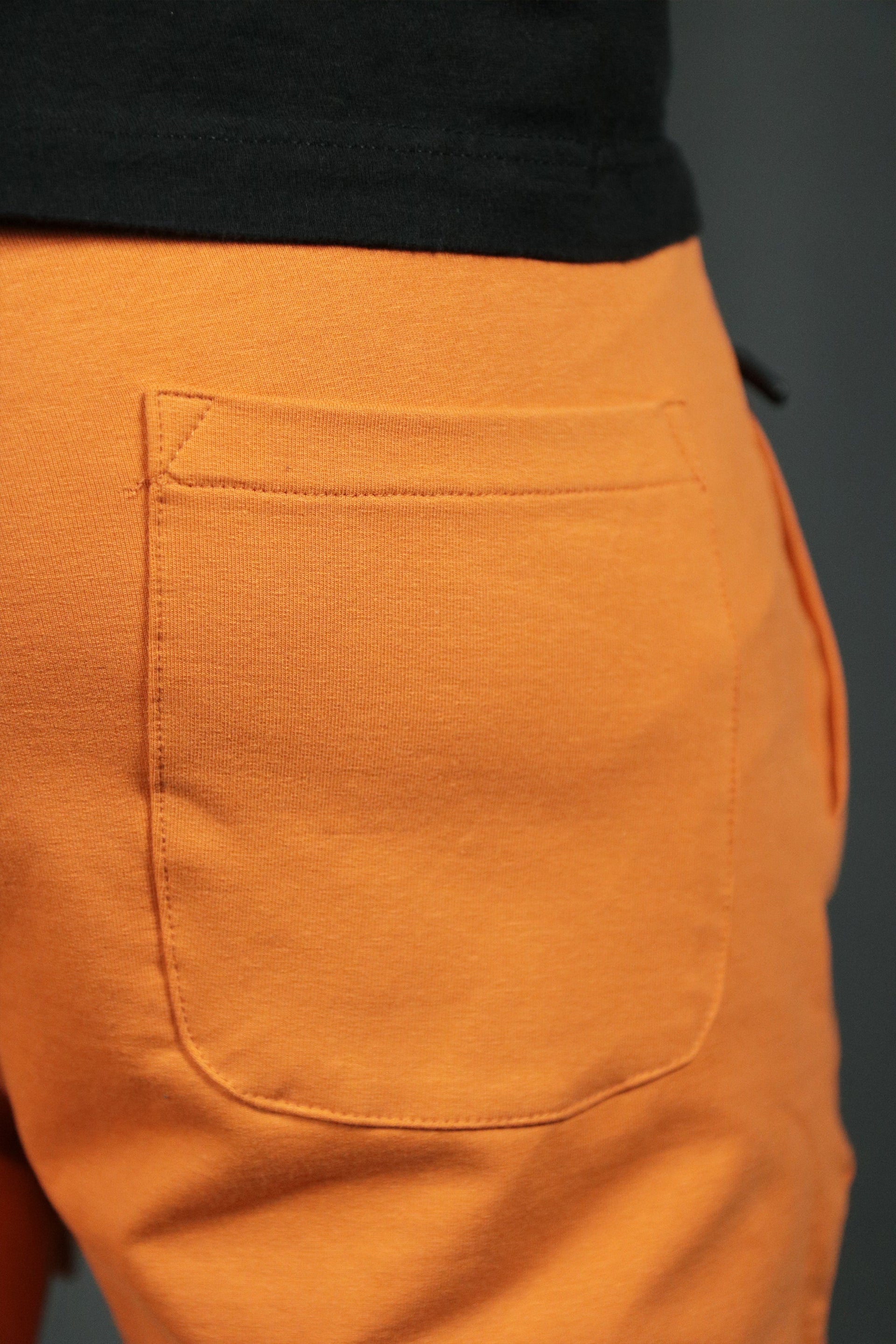 The back pocket of the orange mens terry cloth shorts.