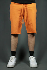 A model wearing the orange men's french terry shorts by Jordan Craig.