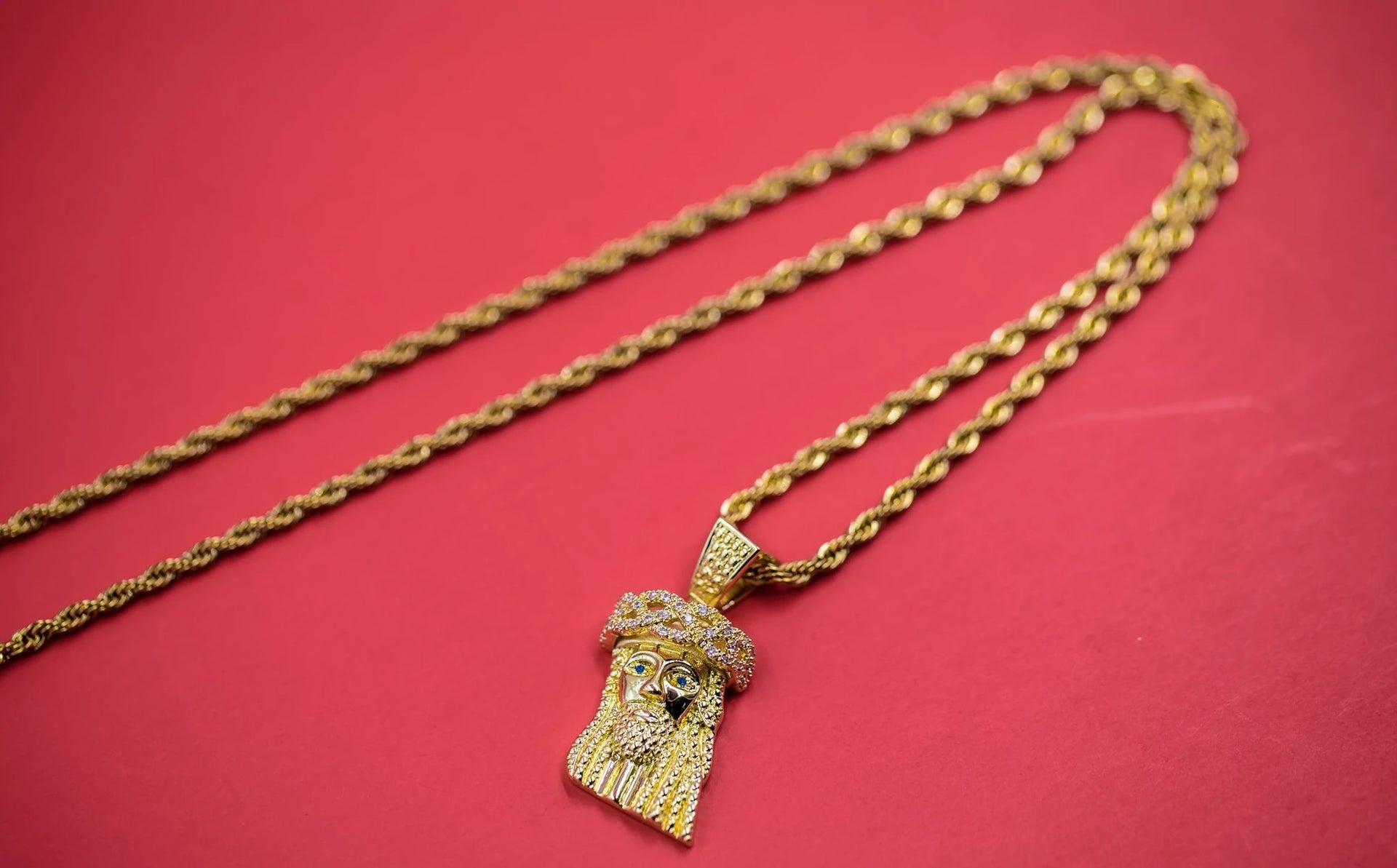 The Iced Out 18K Gold Plated Mini Jesus Piece | Golden Gilt laid out on the ground
